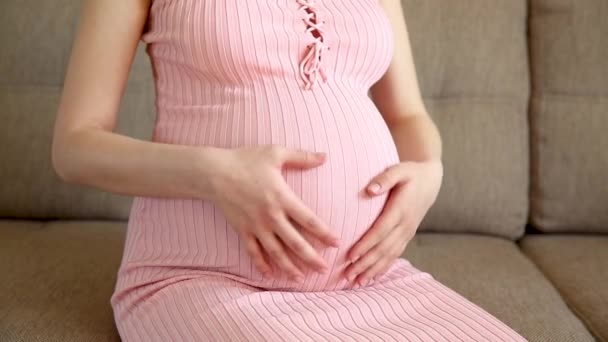 Detailní záběr těhotné ženy hladící její břicho na pohovce - Záběry, video