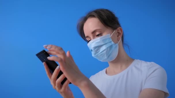 Woman wearing face mask, holding smartphone, using voice recognition function - Záběry, video