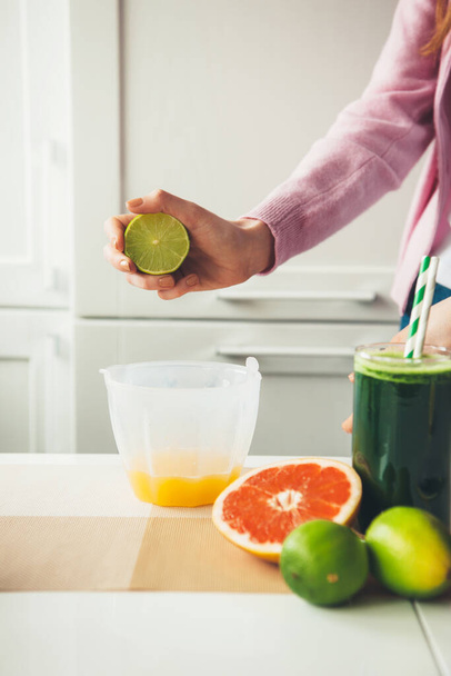 Close photo of a woman squeezing a sliced lime making fresh fruit juice - Foto, imagen