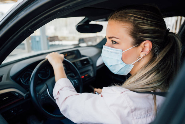  Woman with face mask driving her car during coronavirus pandemic - Valokuva, kuva
