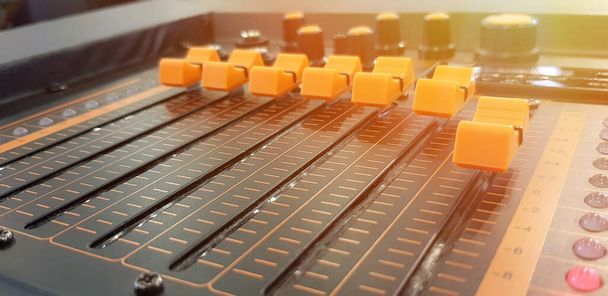 Blurred close up orange button of sound mixer panel equipment for mixing or control audio system with sunlight flare. Technology, Tool and Digital device concept - Φωτογραφία, εικόνα