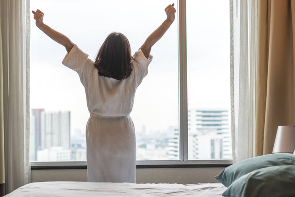 Easy Lifestyle Asiatische Frau wacht am Wochenende morgens auf und erholt sich entspannt im komfortablen City-Hotelzimmer, genießt den faulen Tag der Welt und hat ein ausgewogenes Konzept für die Lebensqualität - Foto, Bild