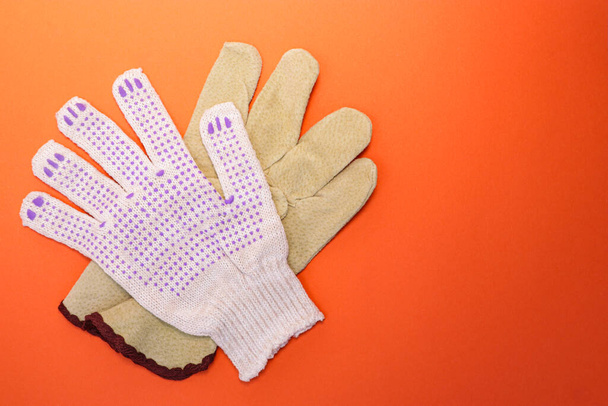 Different types of construction gloves on a bright orange background. Means of protection and security. Copy space for text. Concept for advertising construction. - Photo, Image