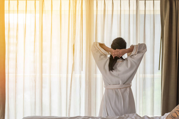 Easy lifestyle Asian woman waking up in the morning taking some rest relaxing in hotel room - 写真・画像