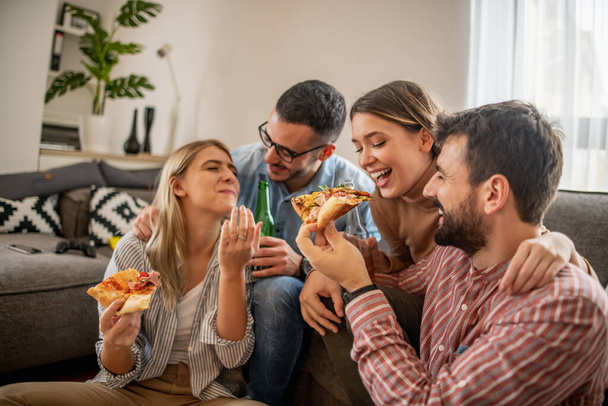 Група друзів, які їдять піцу разом вдома. Люди, стиль життя та концепція нездорової їжі
. - Фото, зображення