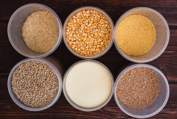 Cereali, in vasetti trasparenti su fondo ligneo, Diversi tipi di cereali crudi per la preparazione del porridge
 - Foto, immagini