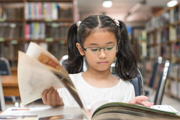 Koncepcja edukacji szkolnej i umiejętności czytania z azjatycką uczennicą uczennicą i czytania książek w bibliotece lub klasie - Zdjęcie, obraz