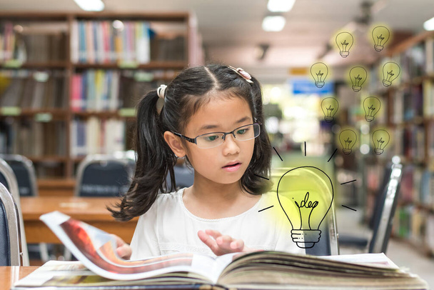 Innowacyjny pomysł na koncepcję prawa autorskiego z dzieckiem zaskoczonym czytaniem książki z żarówką w bibliotece - Zdjęcie, obraz