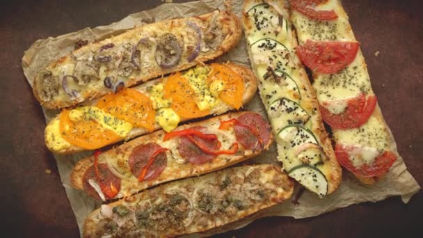 Sortiment von verschiedenen Belägen gebackene Sandwiches. Mit geschmolzenem Käse, Gemüse, Thunfisch, Oliven und Gewürzen - Filmmaterial, Video