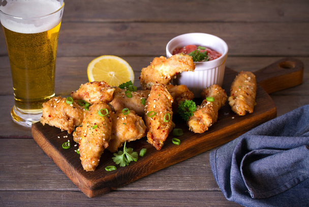 Crispy chicken wings with sauce and glass of lager beer. Horizontal image - Foto, afbeelding