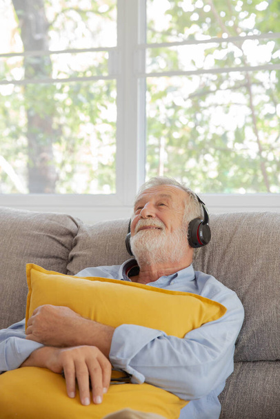 Senior retirement man listen to music using headphone feeling happy in his home - Fotó, kép