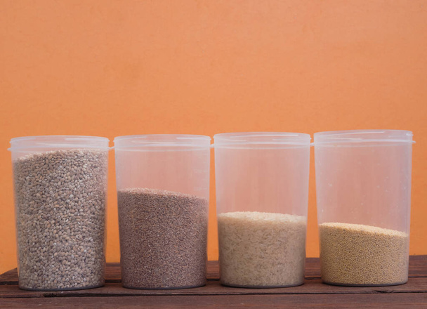 Cereals, in transparent jars on a wooden background, Different types of raw cereals for making porridge - Photo, Image