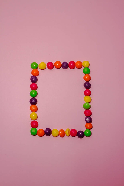 frame of multi-colored candies skills on a pink background - Photo, Image