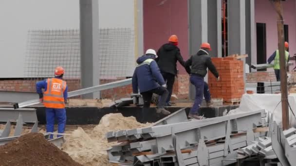 A group of male workers in yellow jackets and helmets is on the construction site. - Imágenes, Vídeo