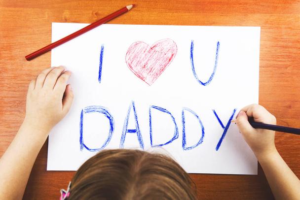 Fathers day concept. Childs hands drawing words I Love U Daddy, and pencils. - 写真・画像