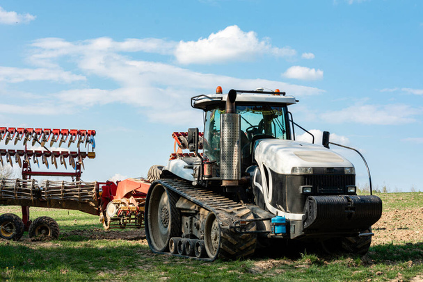 Un trattore cingolato bianco molto grande si trova in un campo in estate mentre coltiva terreni agricoli 2020
 - Foto, immagini