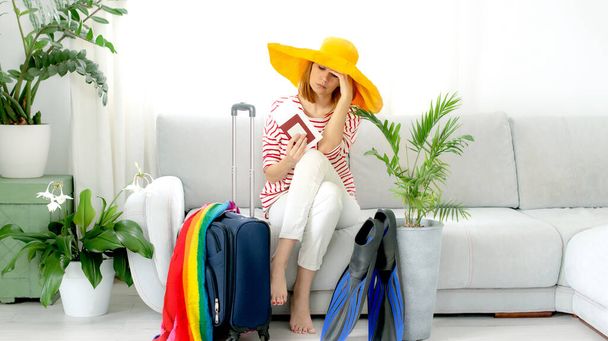 Mooi boos meisje met een gele hoed blijft thuis en plant een reis op vakantie. Sluitingsgrenzen en verbod op vluchten in verband met quarantaine en COVID-19. - Foto, afbeelding
