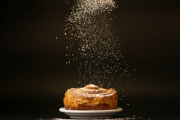 Sweet bread on a white plate on a black background.  - Photo, Image