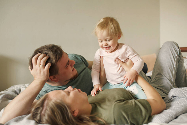 gelukkig familie met kleine meisje kind in de ochtend liggend in slaapkamer en glimlachen - Foto, afbeelding
