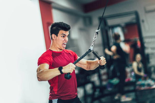 Young handsome man doing exercises in gym - Photo, Image