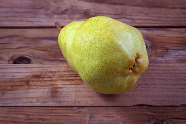 Close-up depicts fresh yellow pear on a wooden background - Fotografie, Obrázek