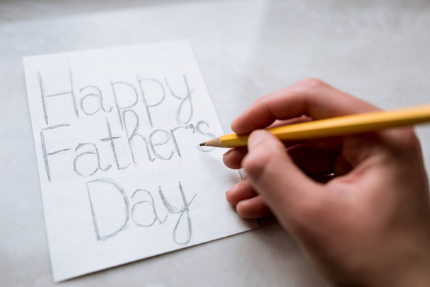 День отца рисует открытку на день отца, рисует оранжевым карандашом, ручная работа - Фото, изображение