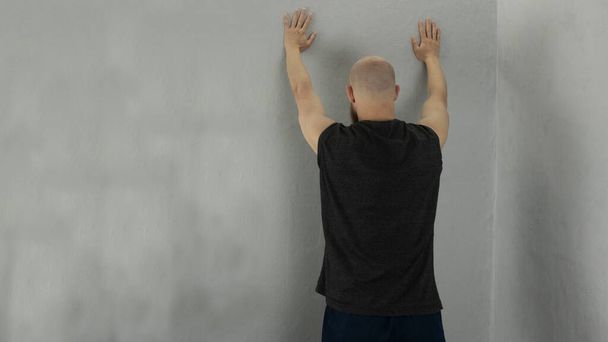 ein Mann steht mit erhobenen Händen an der Wand - Foto, Bild