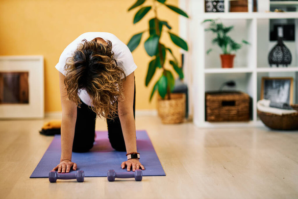 Pregnant middle aged woman kneeling in Box yoga pose. Home interior. - Φωτογραφία, εικόνα