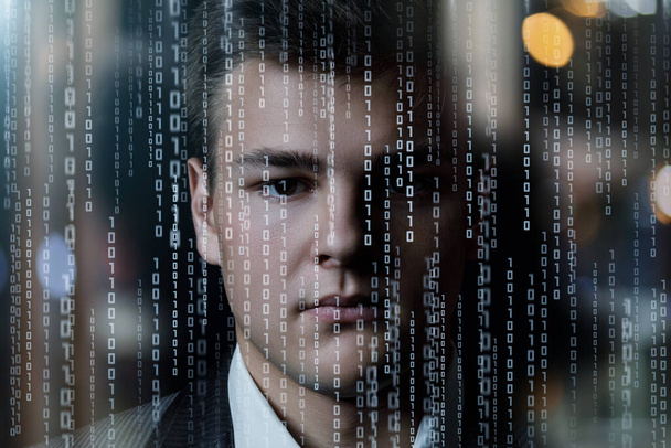 Het gezicht van een jonge zakenman op een achtergrond van binaire codes. - Foto, afbeelding