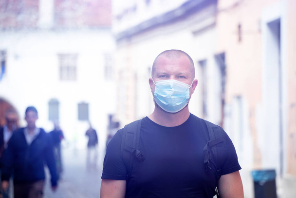 COVID-19 Pandemic Coronavirus. Man in city street wearing face mask protective for spreading of disease virus SARS-CoV-2. Man with protective mask on face against coronavirus disease. - Photo, image
