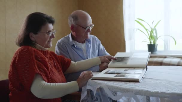 senior couples keeping love and care for each other are inspired by memories of past years, looking at photos in family photo album - Imágenes, Vídeo