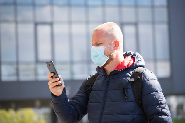 COVID-19-pandemiakonavirus. Turisti käyttää älypuhelinta, yllään kasvonaamio suojaava leviämisen taudin virus SARS-CoV-2.  - Valokuva, kuva