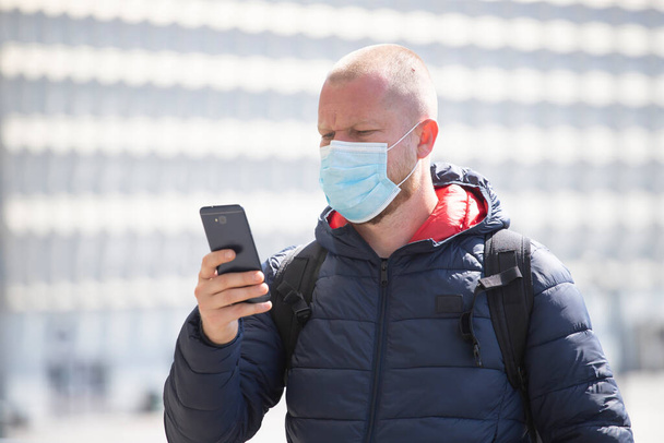 COVID-19 Pandemic Coronavirus. Tourist using the smartphone, wearing face mask protective for spreading of disease virus SARS-CoV-2.  - 写真・画像