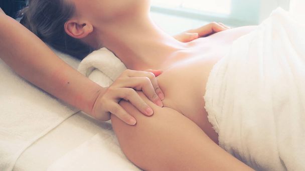 Zrelaksowana kobieta masująca ramiona w luksusowym spa przez profesjonalnego masażystę. Koncepcja wellness, uzdrowienia i relaksu. - Zdjęcie, obraz