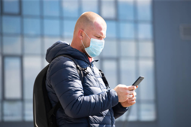 COVID-19 Coronavirus pandemico. Turista utilizzando lo smartphone, indossare maschera protettiva per la diffusione del virus della malattia SARS-CoV-2
.  - Foto, immagini
