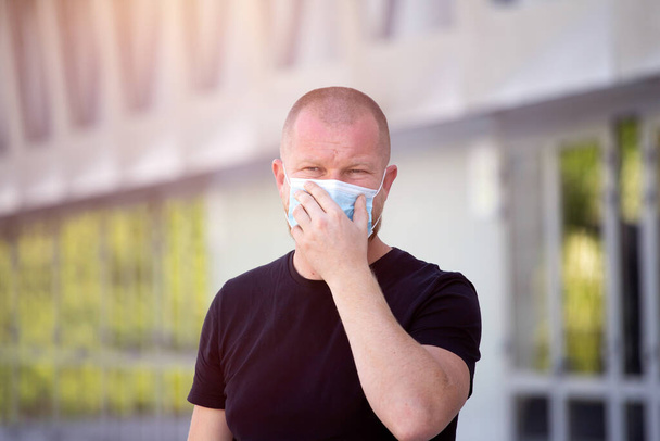COVID-19 Пандемічний коронавірус. Людина перед сучасною будівлею носить маску для обличчя, захищену від поширення вірусу хвороби SARS-CoV-2. Людина з захисною маскою на обличчі проти коронавірусної хвороби
. - Фото, зображення