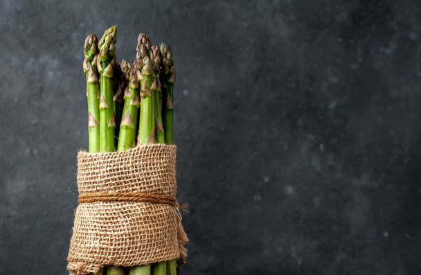 Raw green asparagus on a stone background with copy space for your text. - Фото, изображение