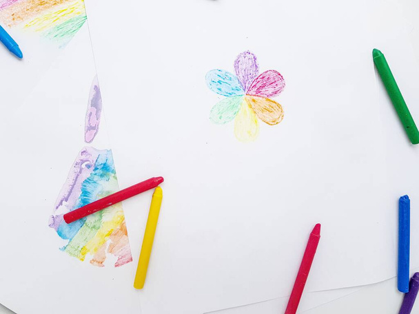 Colored wax crayons. A handprint on a white sheet of paper. - Photo, image