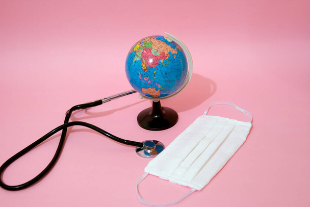 Maschera medica, stetoscopio e globo terra su sfondo pastello
. - Foto, immagini