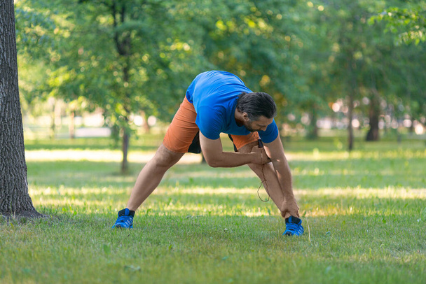 Mężczyzna rozgrzewka przed jogging na świeżym powietrzu w okresie letnim. - Zdjęcie, obraz