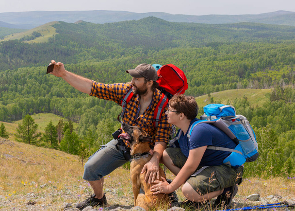 Père avec son fils et leur chien prennent un selfie au sommet de la montagne
. - Photo, image
