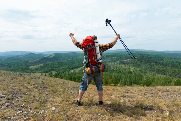Middelbare leeftijd wandelaar backpacker man groeiende handen met trekking palen tijdens grote hoogte acclimatisatie wandeling. - Foto, afbeelding