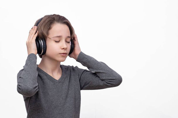 teenager closed his eyes and listens to music on headphones, isolate on a white background, listening, the boy loves loud music - Foto, imagen