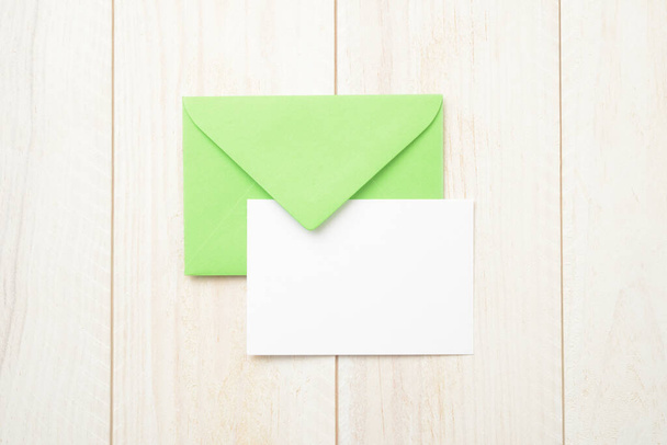 Vihreä kirjekuori ja tyhjä kortti valkoinen puinen pöytä - Valokuva, kuva