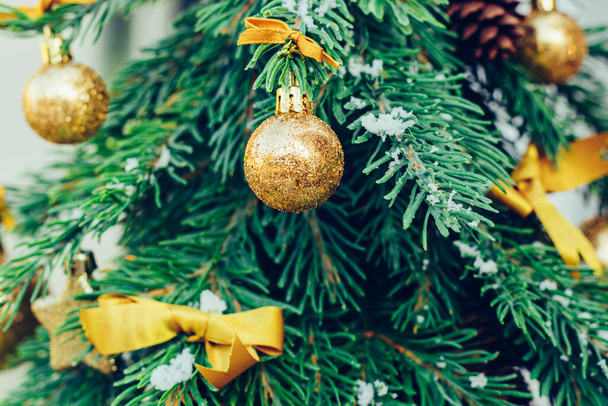 New year wallpaper. Green fir tree background with golden balls and ribbon. - Photo, image