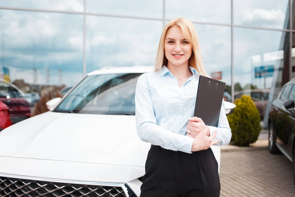 Employee of a car dealership stands in the background of an office and a car - Photo, Image