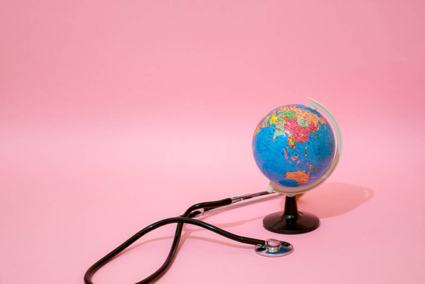 Earth globe with stethoscope on pastel background. - Photo, Image