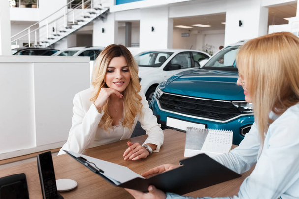 Car dealership seller familiarizes the client with the conditions of car purchase - Zdjęcie, obraz