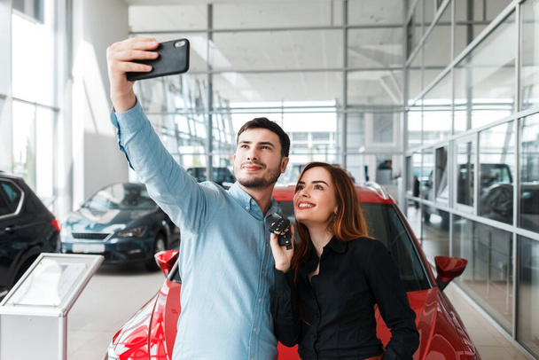 Couple making selfie in a car dealership - Foto, imagen