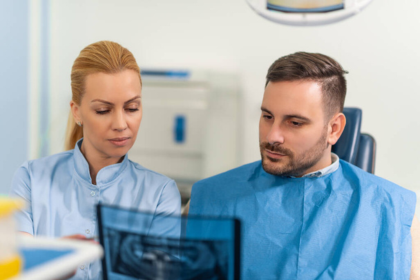 Dentysta wyjaśniający pacjentowi zdjęcie rentgenowskie.Koncepcja zdrowia zębów. - Zdjęcie, obraz
